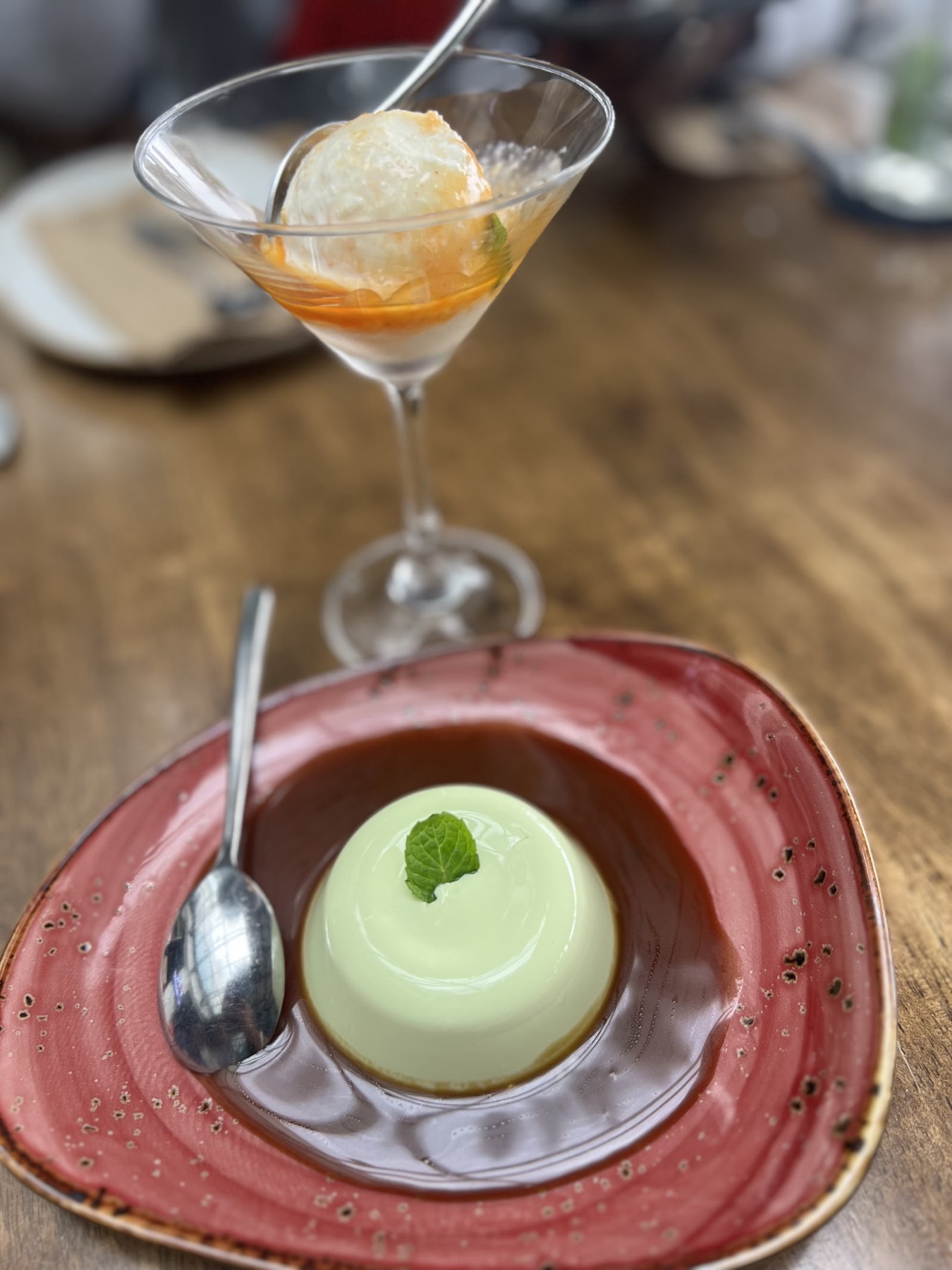 Panna cotta dessert on a red plate beside a mocktail in a coupe glass